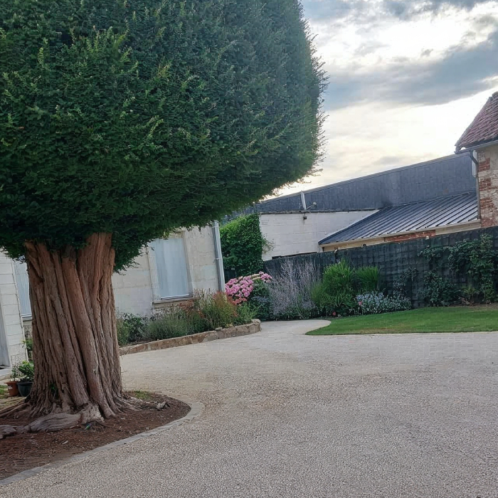 Aménagement extérieur avec cour gravillonnée et massif fleuri par Tharreau Paysagiste